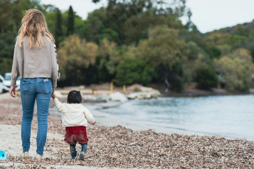 a woman and a child walking on a beach